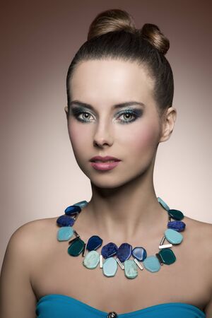beauty portrait of pretty young brunette girl with summer style. Turquoise make-up, stylish necklace and creative hairdoの写真素材