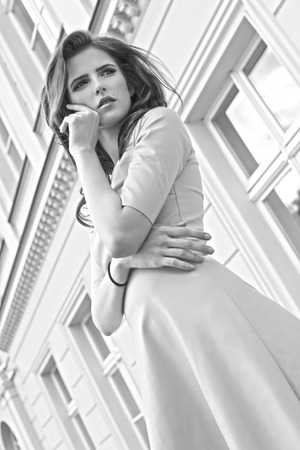 Black and white fashion portrait of a young pretty girl with old building in background , she is looking awayの写真素材