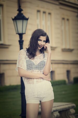 pretty model in casual white dress with shorts , she has an old fashion building on the background and vintage colorの写真素材