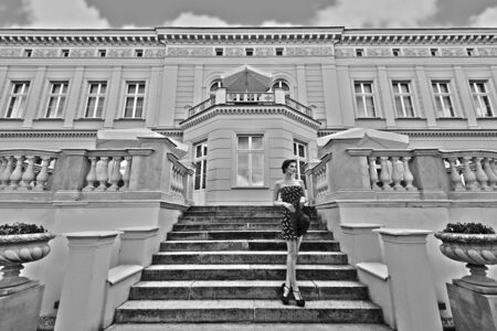 black and white . hdr effect , very cute princess in elegant blue dress with hat , standing on stairs of old bulding , outside and looking far awayのeditorial素材