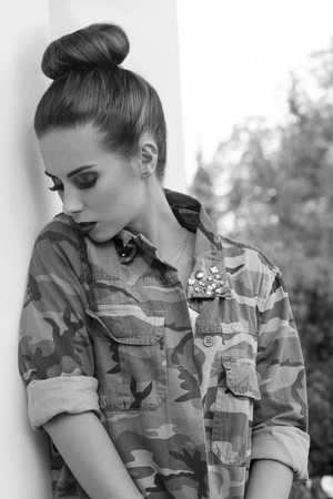 sensual woman posing in outdoor fashion portrait with creative hair-style, rock make-up and streetwear military shirt. In sensual pose , black and white image.の写真素材