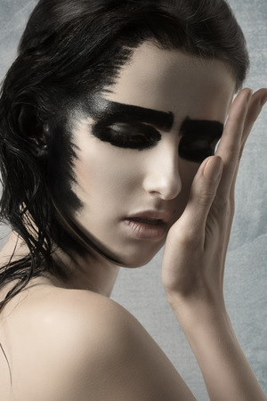 close-up of beauty female with perfect skin and strong painted black make-up on her face and hairの写真素材