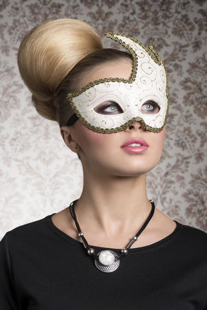 close-up portrait of elegant woman with classic blonde hair-style, necklace and cute decorated mask. Mysterious beautiful womanの写真素材