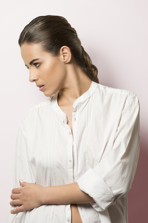 cute fashion portrait of very beautiful female with natural make-up and perfect skin. Turned on her profile wearing white open shirtの写真素材