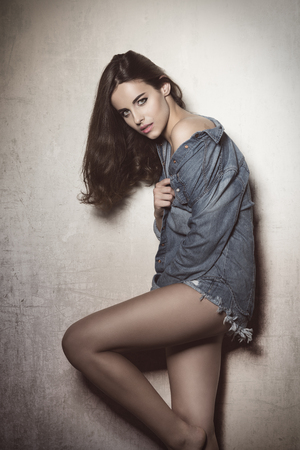 fashion shoot of sensual brunette woman with casual modern style, long natural hair and denim shirt. She is looking in cameraの写真素材