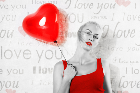 black and white shot , with red part . of sexy blonde girl with heart shaped balloon she looks in to the lens with hair on the face , valentives day conceptの写真素材