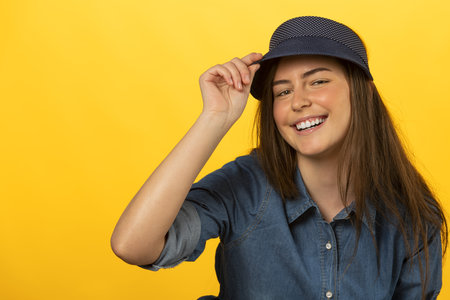 very beautiful smiling girl in summer dress on yellow, she has cap and smile in cameraの写真素材