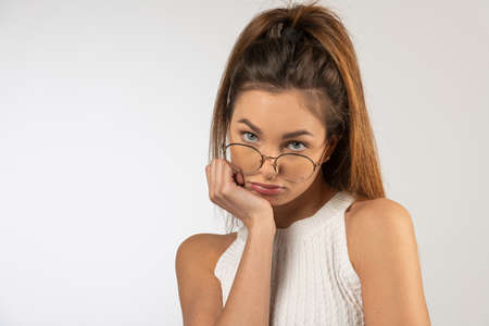 cute young student female with natural hair make up, looking in camera making face angry. she has eyeglassesの写真素材