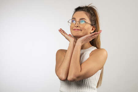 pretty young italian student girl, with eye glasses she is looking up ,. making funny face on white background. natural hair.の写真素材