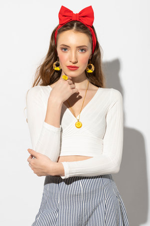 very cute model wearing a white top and a red bow in a fresh summer portrait , she has a yellow jewelry with flowerの写真素材