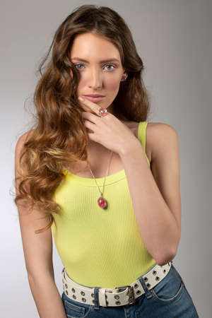 cute young model in casual outfit , with yellow undershirt and jeans , she is posing with pretty summer jewelry looking in camera .の写真素材