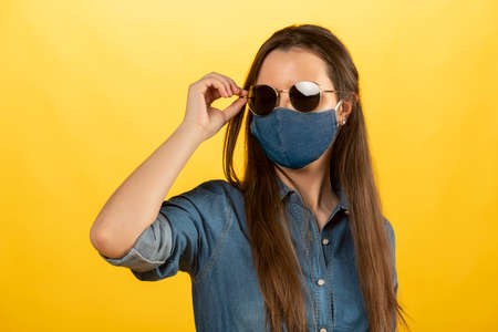 pretty girl in jeans outfit , ready for a summer day , during pandemic , she is wearing a blue mask and sun glassesの写真素材