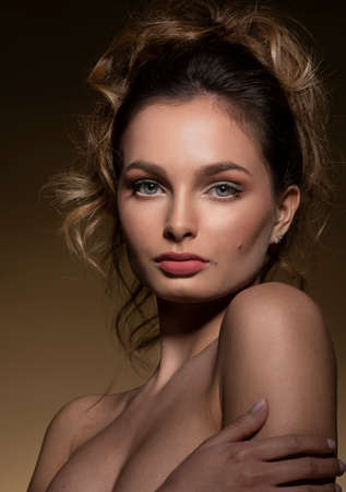 Fashion portrait of young and beautiful girl, with hairstyle, she is looking in camera on dark beaige backgroundの写真素材
