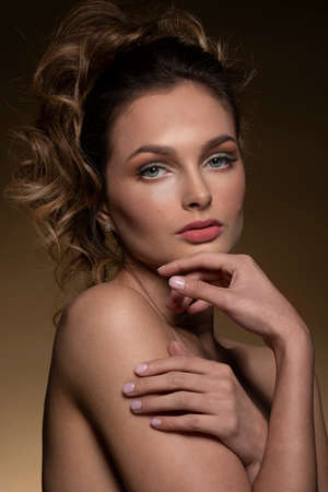 pretty fashion girl in a beauty portrait she is posing ina close-up on beige background, with nice hair styleの写真素材