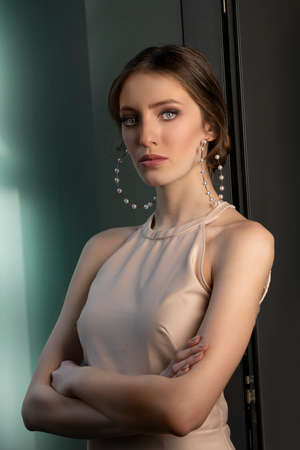 elegant girl in pretty pink dress, with pearls big earrings looking in camera prodly with her stunning blue eyes-の写真素材