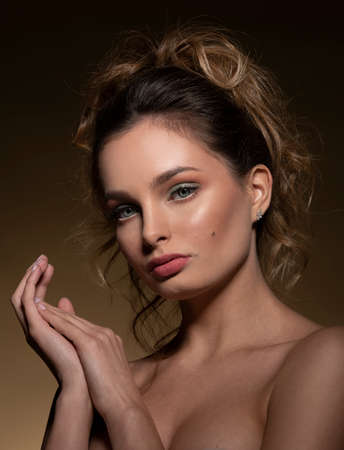 cute fashion model in a attractive portrait with hairdo she is looking in camera posing on dark beige backgroundの写真素材