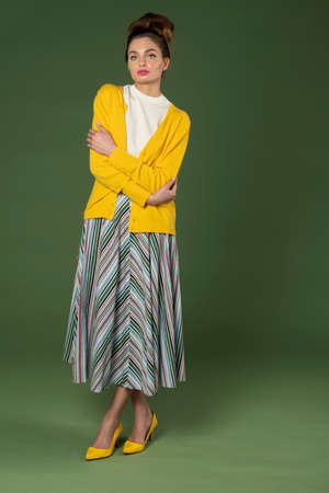 young and beautiful model, with perfect hair style, with old fashion outfit, colorful striped gown and yellow jacket, on green backgroundの写真素材