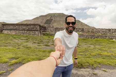 Gay couple holding hands with the Teotihuacan pyramid in the background very happy