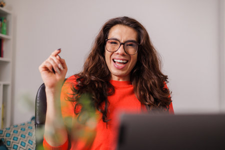 non-binary person behind desk with big smile