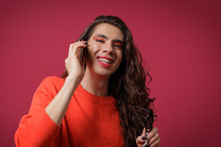 Non-binary person talking on cell phone with a happy expression on their face