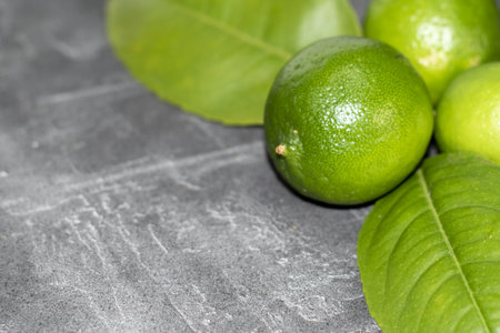 Fresh limes with green leaves on gray table, closeup. Space for textの写真素材