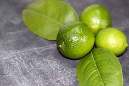 green limes with leaves on a gray background. close-upの写真素材