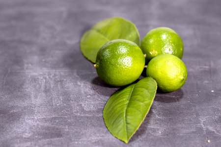 Fresh limes on a gray background. Limes with green leaves.の写真素材