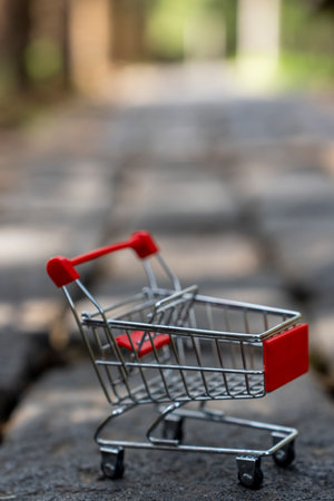 Shopping cart on a wooden stump with a blurred green background.の写真素材