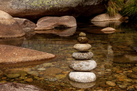 stacked stones in a river with clear and calm waters with reflections