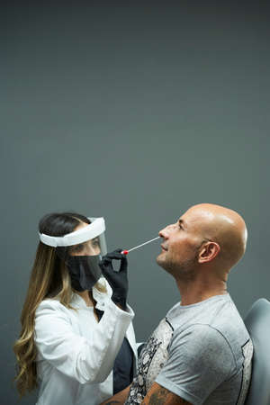 Swab Test virus. Female doctor doing a nasopharyngeal swab test to a male patient. The doctor...