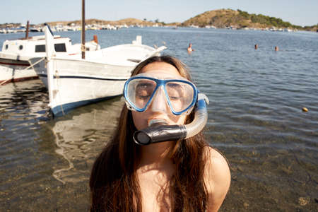 Funny little girl on the beach in a diving mask making a silly face. Closed portrait of a girl on...