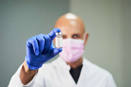 Doctor with blue latex glove showing the Covid-19 cure to prevent disease and spread. Front view.の写真素材