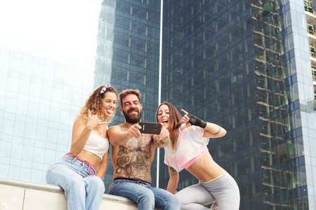 A group of friends who have fun in the streets of the city doing selfie. In the background we see...