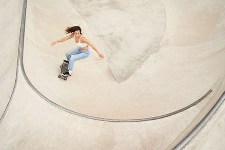 Girl rides a skateboard in the bowl of a skatepark. Gray background.の写真素材