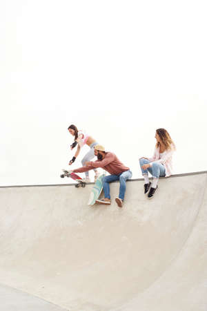 Young people have a great time at the skate park, sitting down laughing.の写真素材