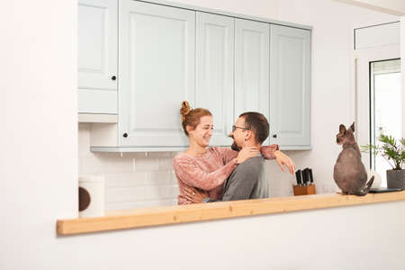 Happy young couple laughing in kitchen at home.