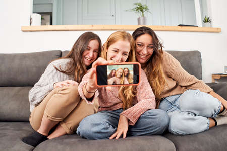 Group of female friends on the sofa at home taking a selfie.の写真素材