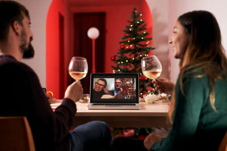Couple celebrating Christmas in quarantine due to covid 19, making a video call to parents and in-laws. New normal in times of coronavirus.の写真素材