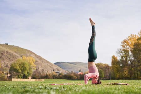 Woman practicing yoga in the park - relaxing in natureの写真素材