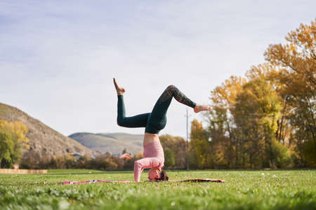 Woman practicing yoga in the park - relaxing in natureの写真素材