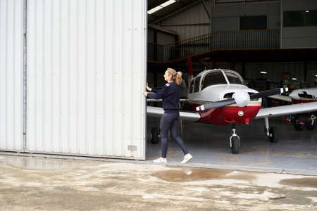Woman opening the door of the hangar where there are several plans.