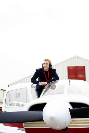 Young female pilot posing on her plane.