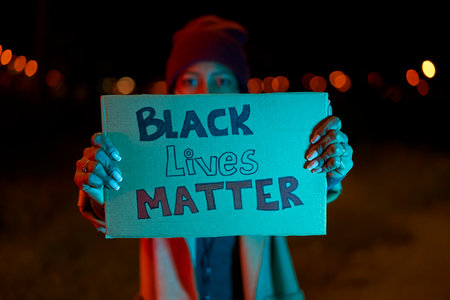 African-American girl holding a banner reading "Black Lives Matter". Demonstration against police brutality, racism and deadly use of force by officers.の写真素材