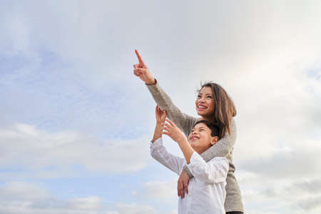 Young mother hugging her child pointing to the sky. Copy space.の写真素材