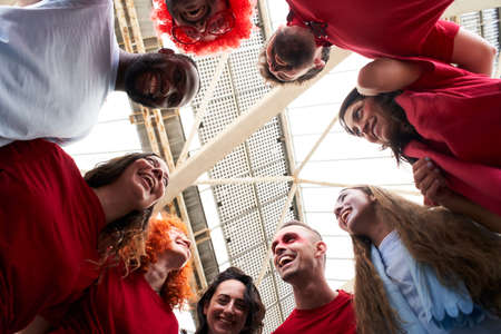 View from below of a group of people celebrating together and hugging while cheering for their...