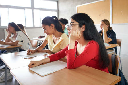 Group of students sitting in class attending to the teacher.の写真素材