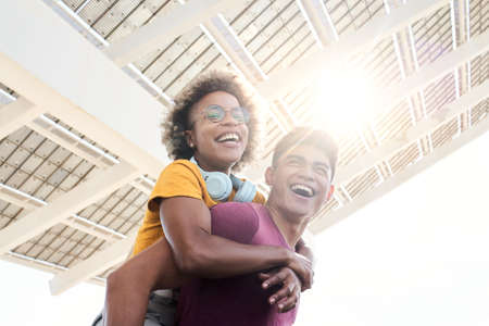 Young smiling lovers looking at the camera. The girl is piggyback on her boyfriend. Concept of friendship and couple relationship having fun.の写真素材