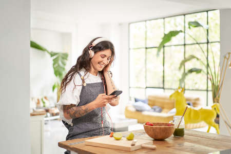 Beautiful young woman listening to music with headphones at home in the morning having a healthy...