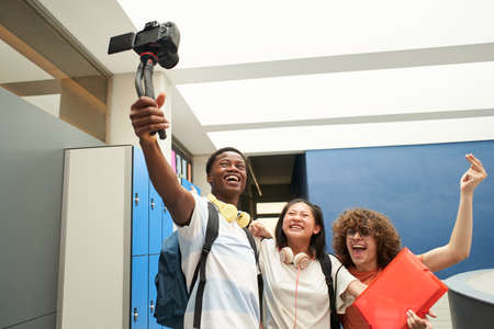 Group of smiling students blogging at school. Multiethnic group of young people recording a video with a professional camera.の写真素材