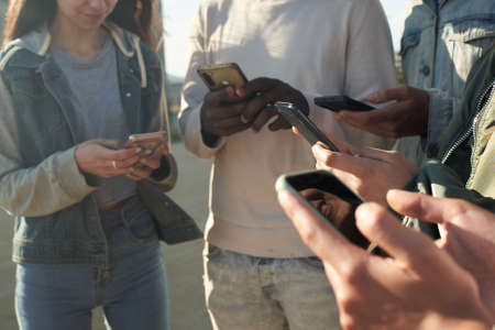 Group of unrecognizable people using and looking al mobile phone together.の写真素材